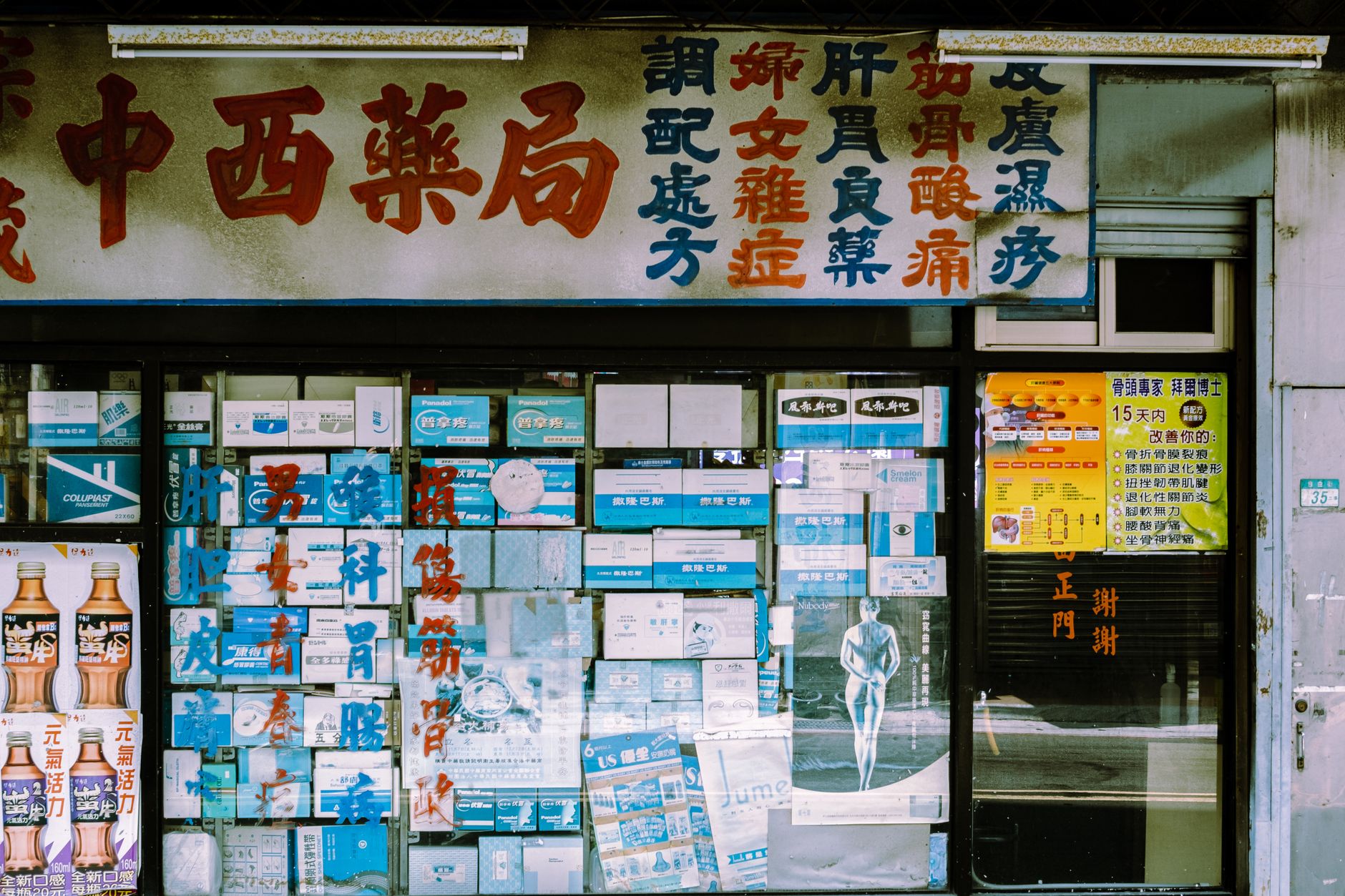 A traditional storefront with decorative signage and posters displayed in the window.